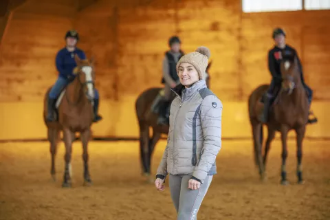 Animatrice qui encadre des jeunes dans apprentissage de l'équitation