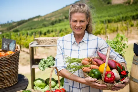 Jeune femme avec un panier sous le bras, rempli de légumes frais