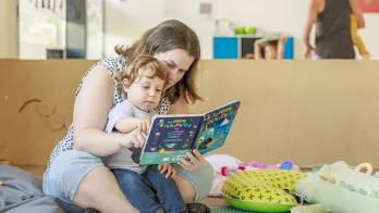 assistante maternelle qui fait la lecture à un jeune enfant