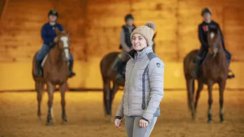 Animatrice qui encadre des jeunes dans apprentissage de l'équitation
