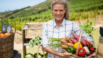 Jeune femme avec un panier sous le bras, rempli de légumes frais